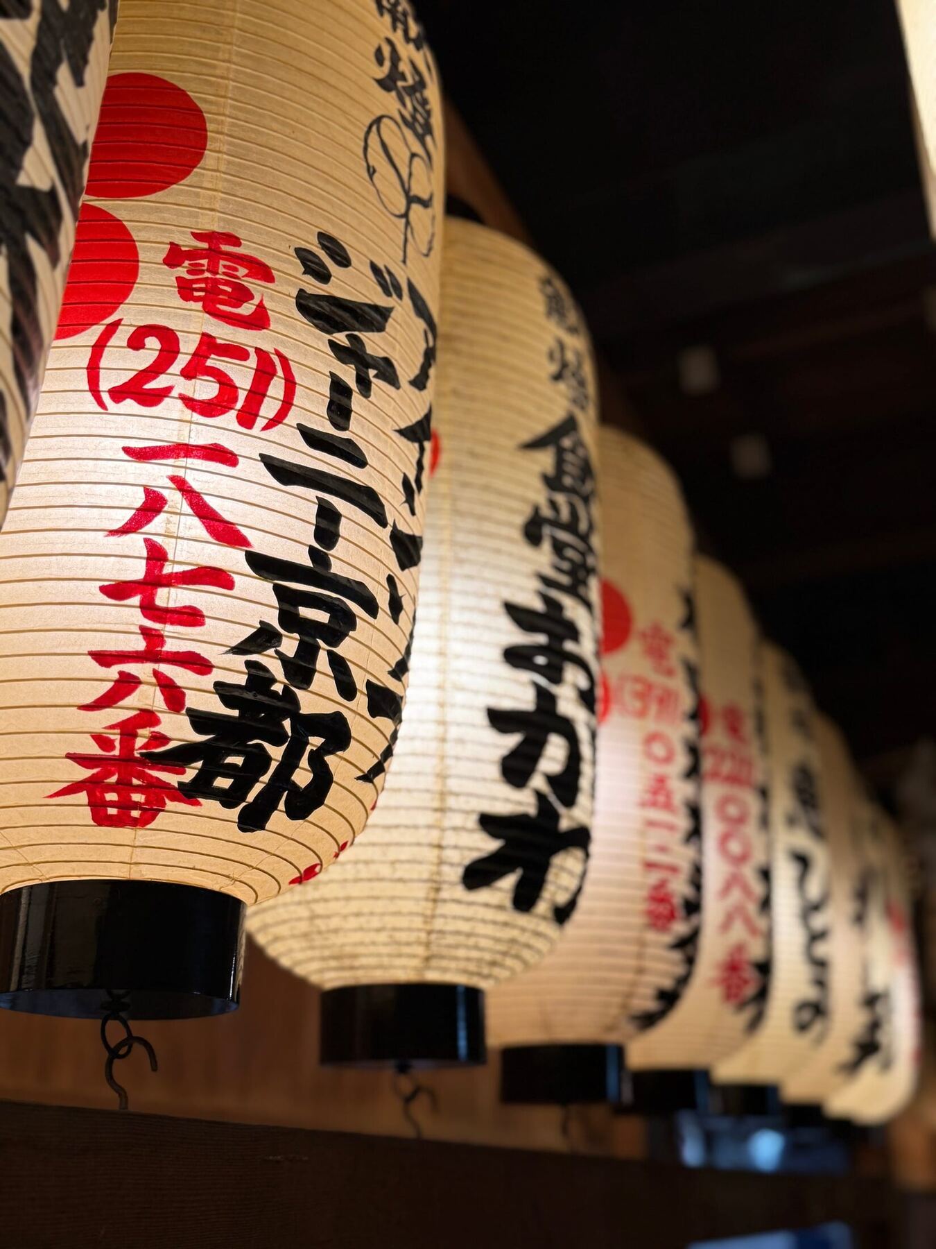 A row of glowing paper lanterns with Japanese calligraphy