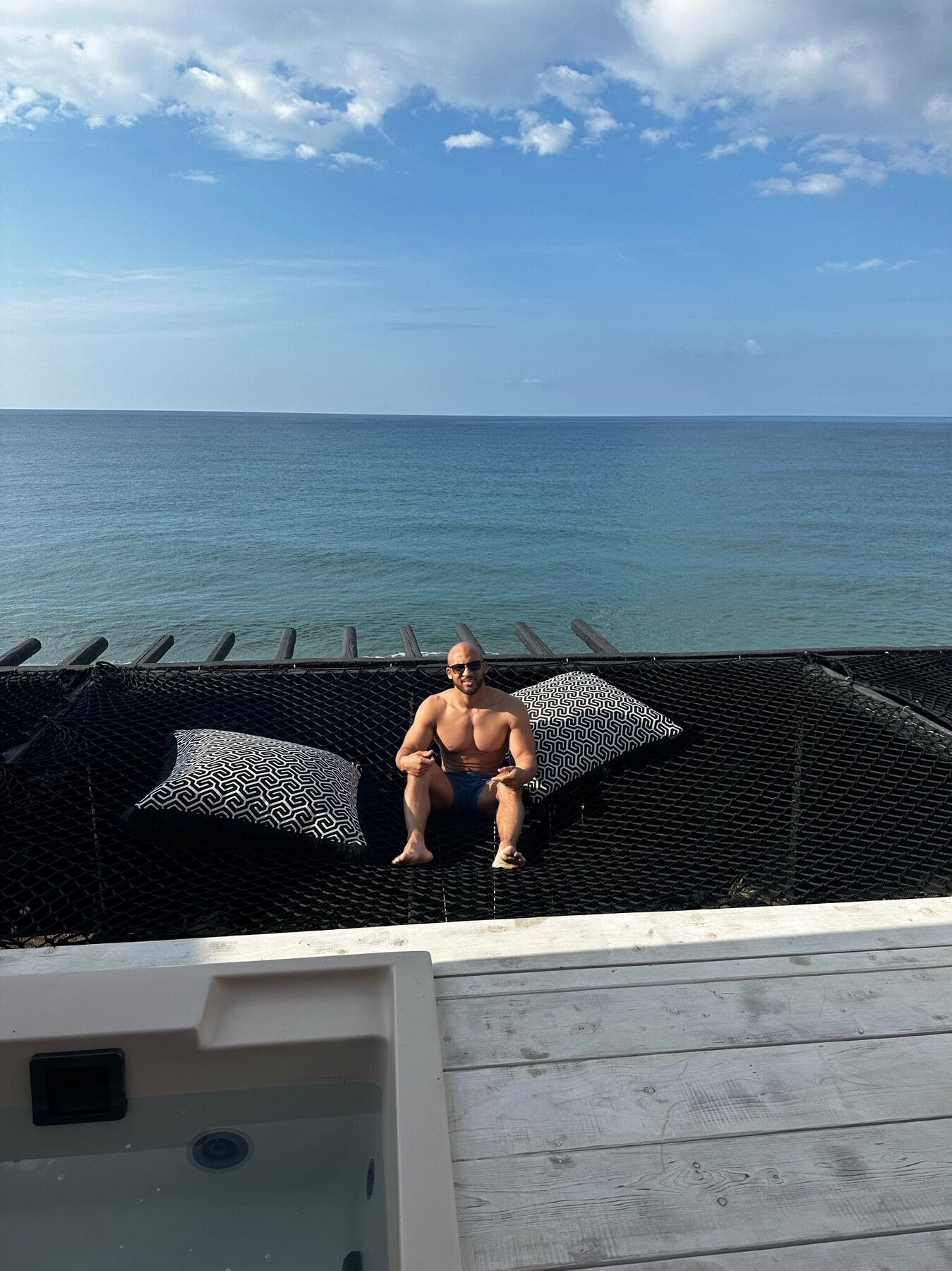 A traveler relaxing on a woven daybed above the Aegean Sea in Mykonos