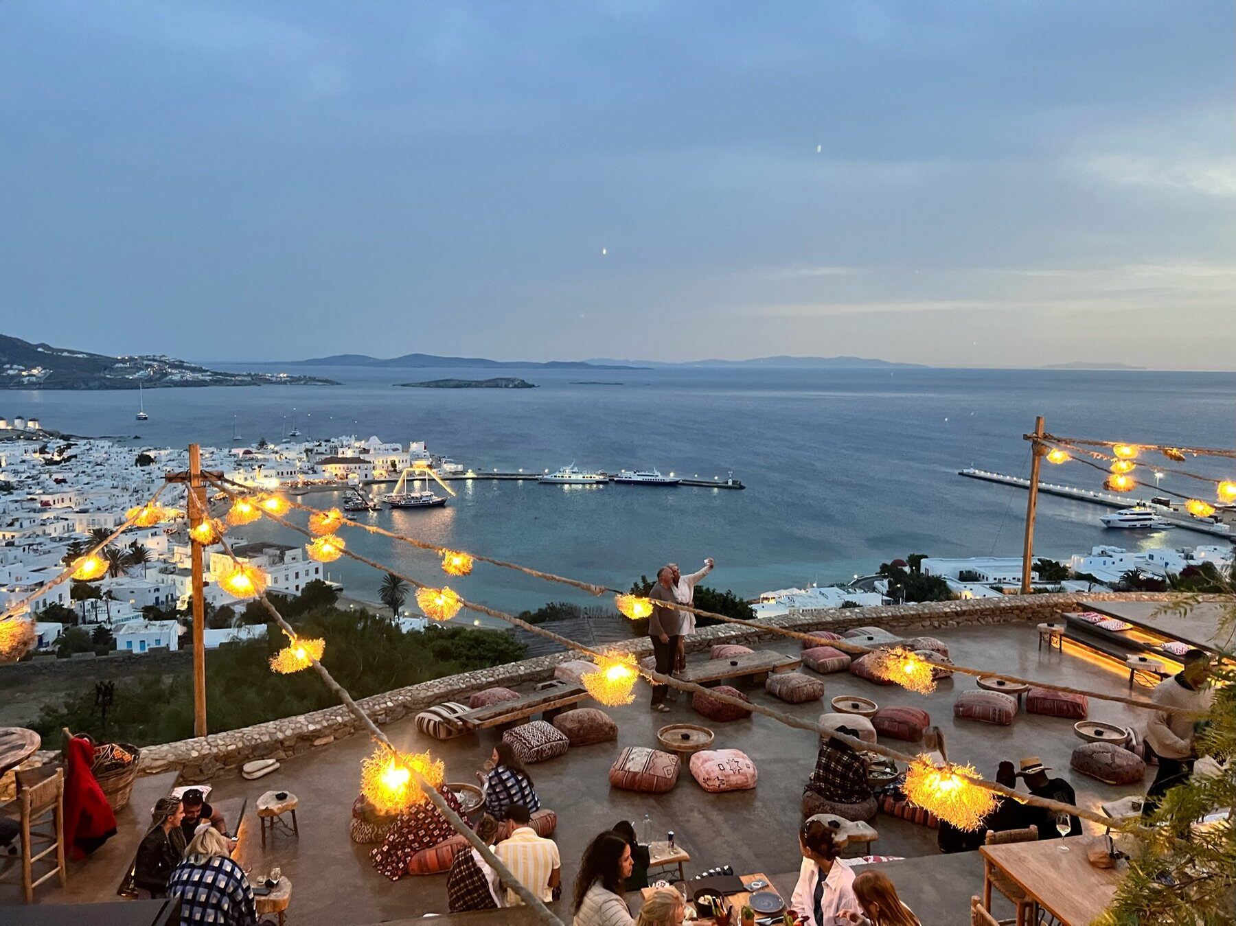Mykonos Town and its harbor seen from a hillside terrace at twilight
